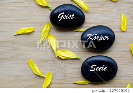 Stacked stones reading mind, body, spirit with yellow petals 127639102
