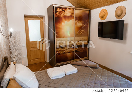 Cozy Bedroom Interior with Sunset Wardrobe and Modern TV, Neutral Colors, Wood Paneling, Relaxing Atmosphere, Contemporary Style Cozy Bedroom Interior with Sunset Wardrobe and Modern TV, Neutral Colors, Wood Paneling, Relaxing Atmosphere, Contemporary Style 127640455