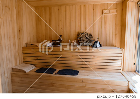 Cozy Scandinavian Sauna Interior: Natural Wood, Benches, Buckets and Towels, Relaxing Wellness Spa Scene in Warm Light, Minimalist Style. Cozy Scandinavian Sauna Interior: Natural Wood, Benches, Buckets and Towels, Relaxing Wellness Spa Scene in Warm Light, Minimalist Style. 127640459
