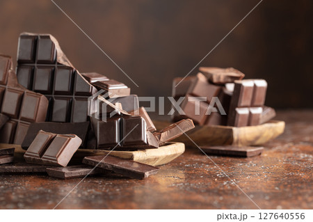 Broken bitter and milk chocolate bars on a brown background. Broken bitter and milk chocolate bars on a brown background. 127640556