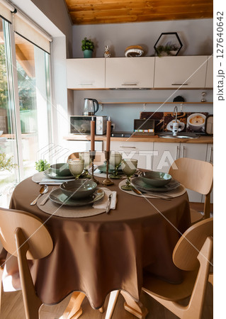 Cozy Rustic Dining Room Interior with Wooden Furniture, Green Table Setting, and Natural Light Kitchen Design, Beige and Brown Color Palette Cozy Rustic Dining Room Interior with Wooden Furniture, Green Table Setting, and Natural Light Kitchen Design, Beige and Brown Color Palette 127640642