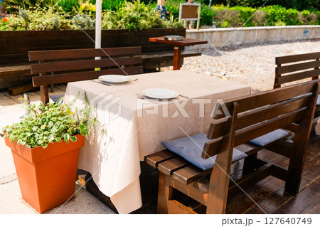 Outdoor restaurant table set for two. Summer dining, natural ambiance, and casual elegance in a sunny garden setting. Outdoor restaurant table set for two. Summer dining, natural ambiance, and casual elegance in a sunny garden setting. 127640749