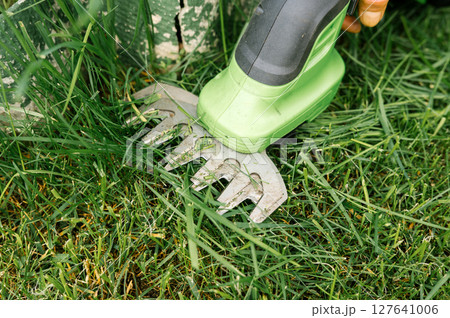 Close-up of electric grass shears cutting lawn for precise garden maintenance 127641006