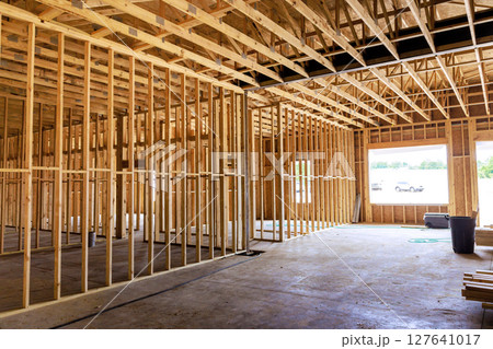Wooden framing structure is taking shape inside building, revealing an open layout under natural light at site. 127641017