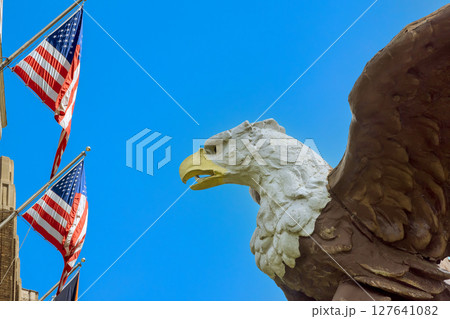 Eagle sculpture towers over American flags, creating patriotic atmosphere in an urban setting Eagle sculpture towers over American flags, creating patriotic atmosphere in an urban setting 127641082
