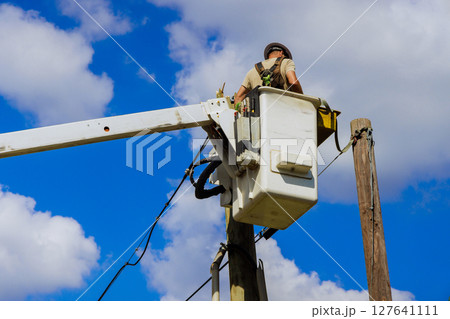 Worker is in lift, conducting repairs on power lines while ensuring safety efficiency after hurricane 127641111
