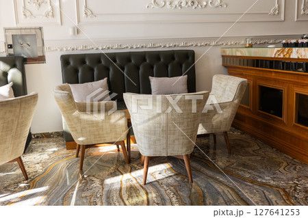 Morning sun lights up elegant cafe seating. Cozy atmosphere, stylish comfort, and relaxed social interaction in a chic modern interior. Morning sun lights up elegant cafe seating. Cozy atmosphere, stylish comfort, and relaxed social interaction in a chic modern interior. 127641253