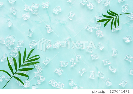 淡いブルーのマーブル調の背景に氷とテーブルヤシの葉 127641471