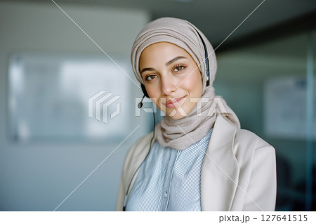 A woman wearing a headset and a scarf is smiling 127641515