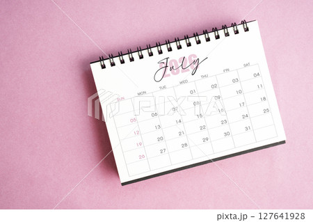 Top view of July 2026 desk calendar on pink pastel background. Top view of July 2026 desk calendar on pink pastel background. 127641928