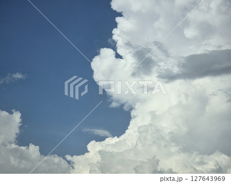 Fluffy white clouds against bright blue sky create serene atmosphere, evoking sense of peace and tranquility. cloud formations are captivating and dynamic 127643969