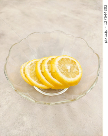 Lemon slices resting in glass bowl on marble countertop 127644802