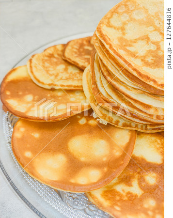 Stack of pancakes showing cooking spots on glass plate 127644816