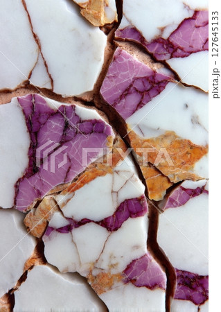 Cracked Calacatta Viola marble surface with purple veins and golden details in closeup composition 127645133