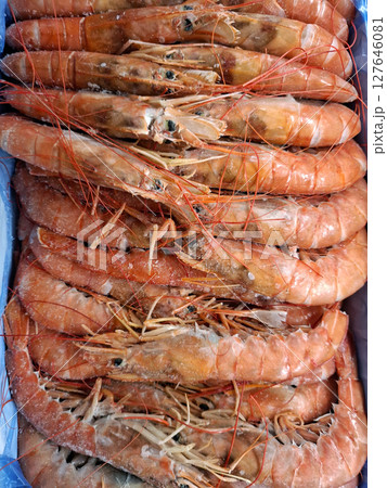 Frozen shrimp is neatly arranged in a box within a grocery store in Spain, highlighting the availability of fresh seafood for shopping. Customers seek delicious meal options. 127646081