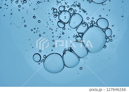 A beautiful drop of cosmetic product with bubbles on a blue background. A beautiful drop of cosmetic product with bubbles on a blue background. 127646288