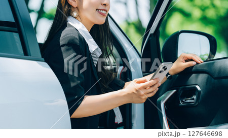 スマートフォンを持って車を降りる女性・ビジネスウーマン スマートフォンを持って車を降りる女性・ビジネスウーマン 127646698