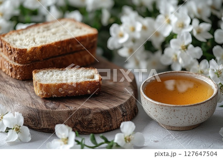 A cozy breakfast setup with bread and tea amidst blooming flowers 127647504