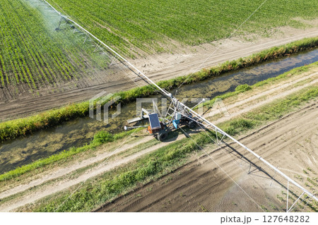 Autonomous machine is moving watering pivot along irrigation canal 127648282