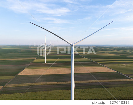 Aerial view of wind turbine on an agricultural filed at sunset. Close up of blades. Aerial view of wind turbine on an agricultural filed at sunset. Close up of blades. 127648312