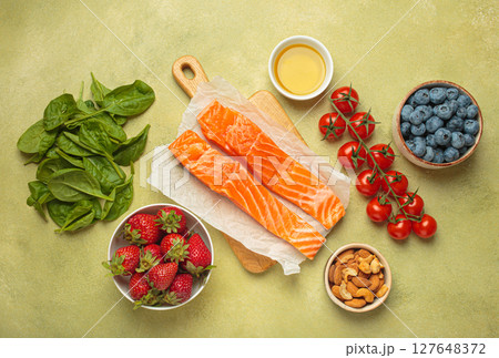 Healthy food for anti inflammatory diet: fish, vegetables, berries, nuts, olive oil, spinach top view on green background 127648372