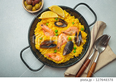 Spanish seafood Paella with shrimps, mussels, peas and lemon in a pan on grey rustic background top view Spanish seafood Paella with shrimps, mussels, peas and lemon in a pan on grey rustic background top view 127648378