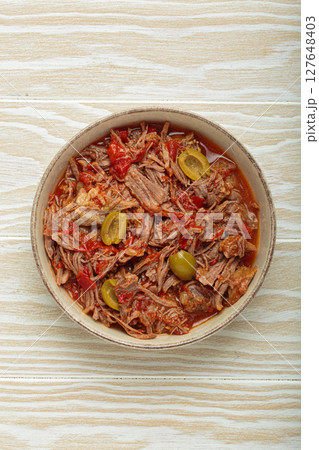 Ropa vieja with white rice, tomato sauce and green olives on a plate top view, traditional dish of Cuba 127648403