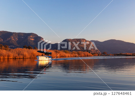 Touristic boat trip on sunset by Dalyan River from ancient Greek city Kaunos in Caria to Iztuzu or Turtle beach. Popular place for family travel on summer vacation. Dalyan, Mugla, Turkey 127648461