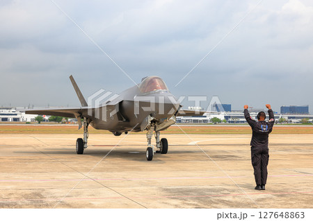 Airbase marshalling supervisor at the airbase apron on duty to take F35 taxiing to the parking place. Airbase marshalling supervisor at the airbase apron on duty to take F35 taxiing to the parking place. 127648863