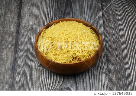 White gluten free vermicelli made from rice flour. Italian pasta in wooden spoon on dark textured background. Top view, space for text. White gluten free vermicelli made from rice flour. Italian pasta in wooden spoon on dark textured background. Top view, space for text. 127649035