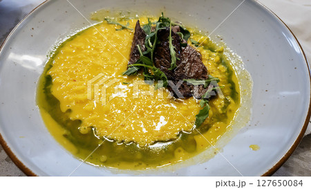 A bowl of hearty pea soup with smoked meat, served with bread. 127650084