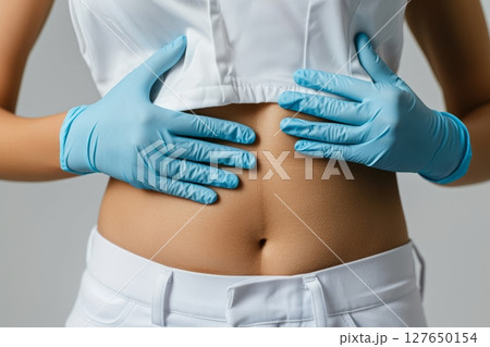 A doctor in blue gloves is closely examining a patient's abdomen, focusing on health and well-being during the check-up Generative AI 127650154