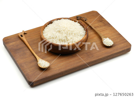 Raw white rice on wooden background. Long uncooked rice in wooden plate. Natural organic food. Traditional Asian cereal culture. Raw white rice on wooden background. Long uncooked rice in wooden plate. Natural organic food. Traditional Asian cereal culture. 127650263