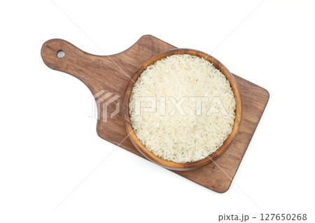 Raw white rice on wooden background. Long uncooked rice in wooden plate. Natural organic food. Traditional Asian cereal culture. 127650268