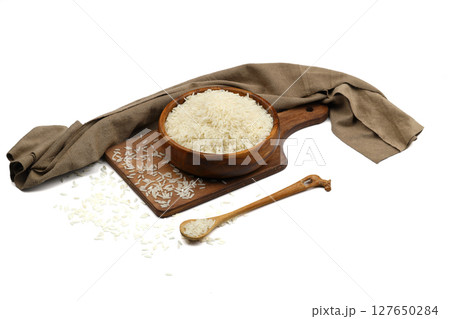 Raw white rice on wooden background. Long uncooked rice in wooden plate. Natural organic food. Traditional Asian cereal culture. 127650284