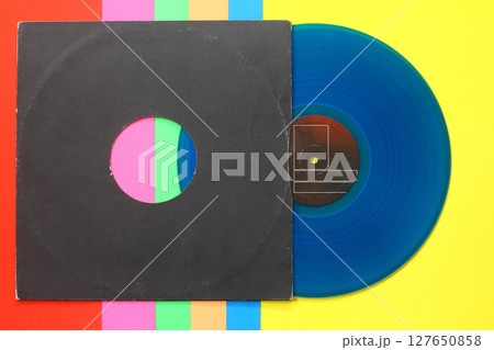 Aged black paper cover and blue vinyl LP record isolated on colorful background 127650858