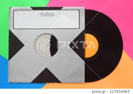 Aged black paper cover and black vinyl LP record isolated on colorful background 127650863