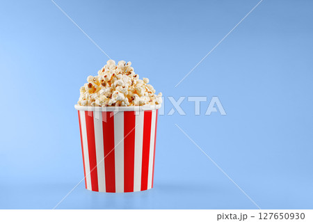 Classic red striped popcorn cardboard cup on blue background Classic red striped popcorn cardboard cup on blue background 127650930
