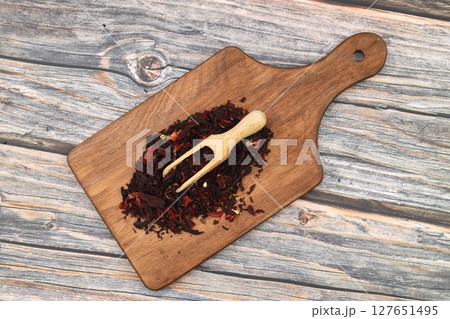 Karkade tea. Hibiscus tea leaves in wooden scoop isolated on wooden background. File contains clipping path. Top view. 127651495