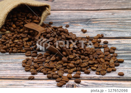 Close-up and top view of hot black coffee in blue coffee cup and roasted Thai coffee beans on wooden background. 127652098