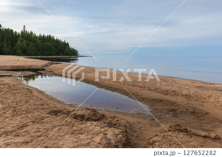 Peaceful scene of a sandy beach with reflective water pools, Ladoga lake coast 127652282