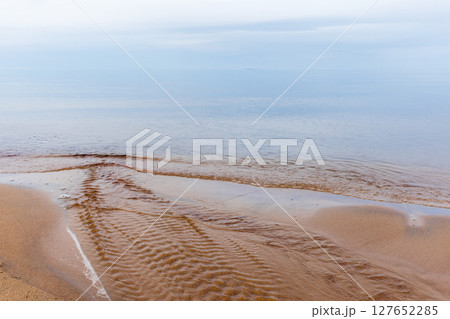 Peaceful scenery featuring calm coastal water meeting golden sands 127652285