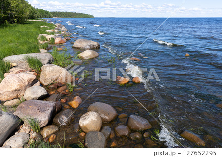 A picturesque view of a rocky lake coastline bordered by calm blue waters 127652295