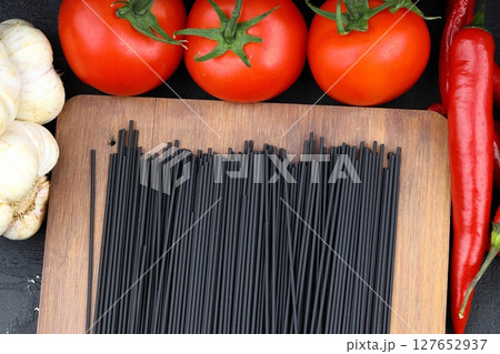 Raw black homemade spaghetti bunch isolated. Dry black noodles macaroni bundle. Close-up Raw black homemade spaghetti bunch isolated. Dry black noodles macaroni bundle. Close-up 127652937