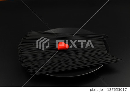 Raw black homemade spaghetti bunch isolated. Dry black noodles macaroni bundle. Close-up Raw black homemade spaghetti bunch isolated. Dry black noodles macaroni bundle. Close-up 127653017