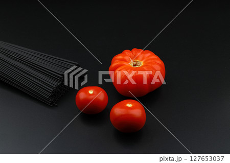 Raw black homemade spaghetti bunch isolated. Dry black noodles macaroni bundle. Close-up Raw black homemade spaghetti bunch isolated. Dry black noodles macaroni bundle. Close-up 127653037