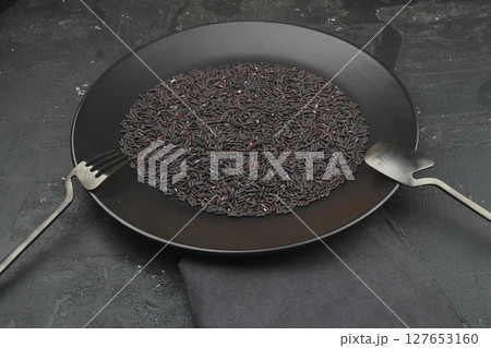 pile of black rice in a wooden bowl on a wooden table close-up 127653160