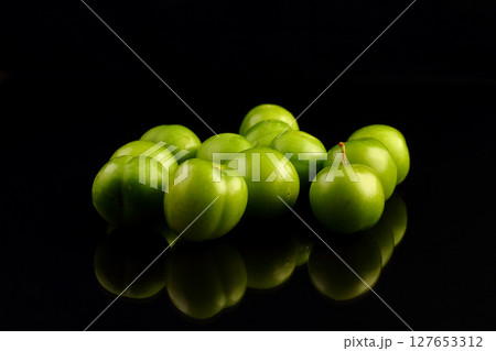 Green plums on black background Green plums on black background 127653312