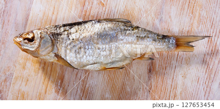 Dried salted fish on wooden background Dried salted fish on wooden background 127653454