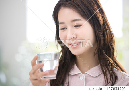 寝起きに水を飲むパジャマの若い女性 寝起きに水を飲むパジャマの若い女性 127653992